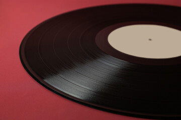 Classic vinyl record close-up on a red burgundy background, outdated data storage, music