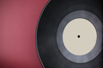 Classic vinyl record close-up on a red burgundy background, outdated data storage, music