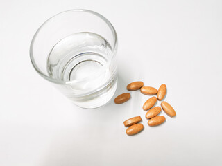 Herbal supplement and a glass of water against white background. Medical concept.