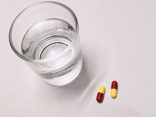 Pills and a glass of water against white background. Medical concept.