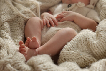 Adorable newborn baby lying on knitted plaid, closeup