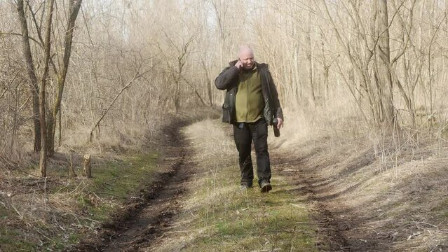 a man argues with someone on a mobile phone and gesticulates emotionally in the forest