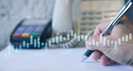 Double exposure of financial graph drawings and a desk with a working notebook in the background. The currency market concept