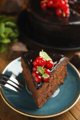Piece of tasty homemade chocolate cake with berries and mint on wooden table, closeup. Space for text