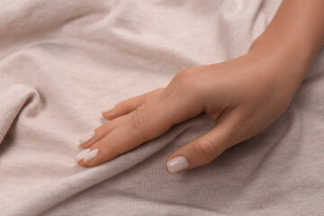 Woman touching soft beige fabric, closeup view