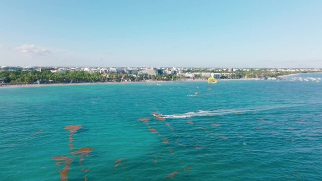 Motorboat dragging parasail parachute above turquoise Playa Del Carmen bay