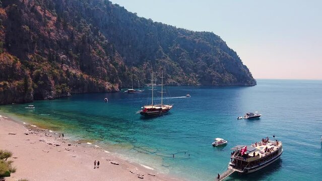 Aerial dolly shot of paradisiacal sandy beach in Turkey with boats anchored in the turquoise sea