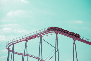 Pink pastel looping roller coaster on blue sky sunny day retro tone. Enjoy travel holiday concept.