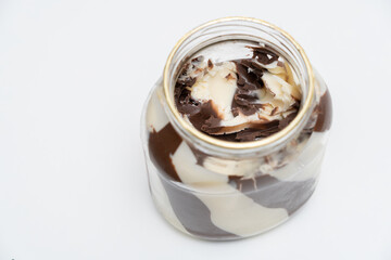 An open jar of milk chocolate paste on a white table.