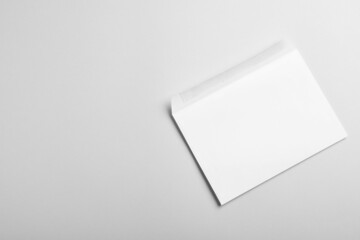 White paper envelope on light grey background, top view. Space for text