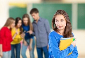 Lonely sad schoolgirl while all her classmates ignored her. Social exclusion problem. Bullying at school concept.