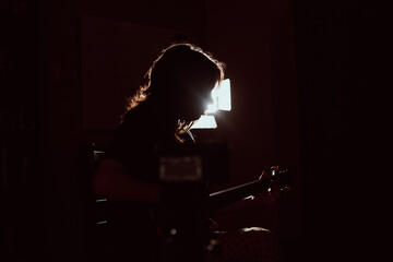 Silueta de joven mujer tocando una guitarra electrica