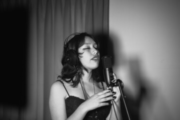 Mujer joven cantando contenta en un estudio musical a blanco y negro - obrazy, fototapety, plakaty