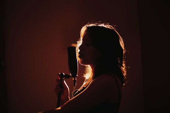 silueta de Joven cantante apasionada a contraluz