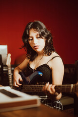 Obraz na płótnie Canvas Joven mujer tocando el bajo en un estudio musical