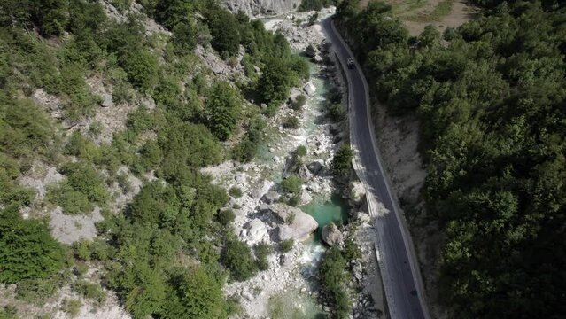 Video with drone of front plane bird's eye view discovery on the Valbone river, Albania, attached to the road. crystal clear turquoise blue water.