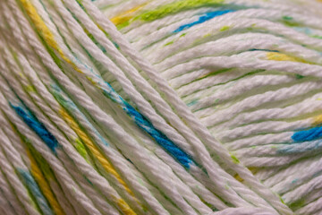Full frame defocused macro texture background view of a small skein of white, blue, and yellow cotton yarn
