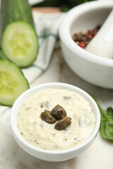 Creamy caper sauce in bowl on white table, closeup