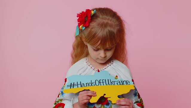 Sad toddler Ukrainian girl kid patriot in embroidery dress protesting war conflict raises banner with inscription massage text on map Hands Off Ukraine. Peace no war, stop aggression. Fight for rights