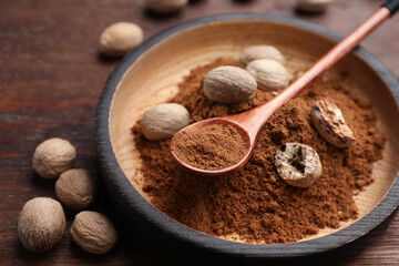 Nutmeg powder and seeds on wooden table, closeup