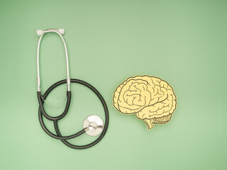 A stethoscope and brain shape made from paper over a green background