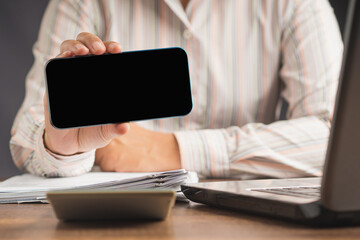 Close-up of hand holding a horizontal mobile phone with a blank black screen