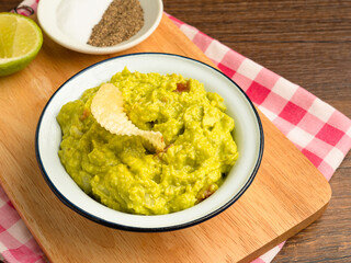Fresh guacamole in a bowl on a wooden cutting board