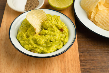 Fresh guacamole in a bowl on a wooden cutting board