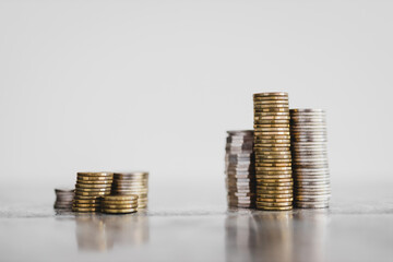 stacks of different coins divided between a small and a big group on white background, good vs bad...