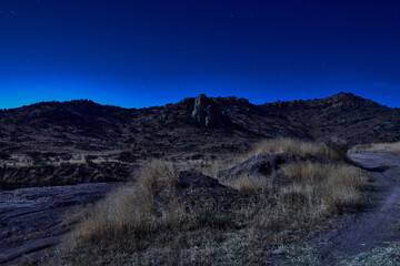 paisaje nocturno desertico parecido al viejo oeste con montañas en el fondo bajo la luz de la luna 