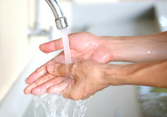 Hands of woman wash their hands in a sink with foam to wash the skin and water flows through the hands. Concept of health, cleaning and preventing germs and coronavirus from contacting hands