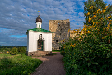 Fototapeta na wymiar View of the Chapel of the Korsunskaya Icon of the Mother of God against the background of the Talavskaya Tower and the wall of the Izborsk fortress on a sunny summer day, Izborsk, Pskov region
