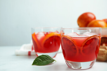 Tasty sicilian orange juice with ice cubes and fruits on white table, space for text