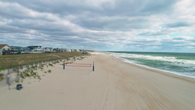 Low aerial view moving backwards over empty Long Beach Island NJ coast, 4K