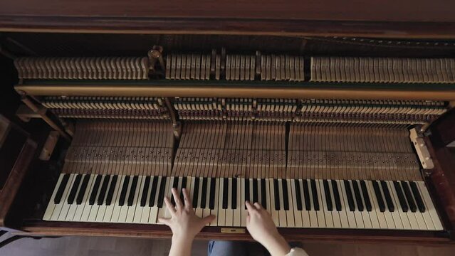 Woman play on open vintage wooden piano