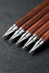 A set of expensive military pens made of rare wood, compositions on a dark background with attributes. Luxury gift pen.