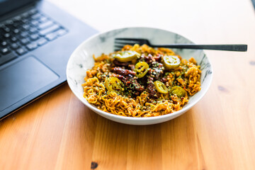 eating instant noodles with sundried tomatoes and jalapenos while working from home on a laptop, remote working or lunch at the office