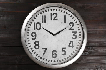 Stylish analog clock hanging on wooden wall