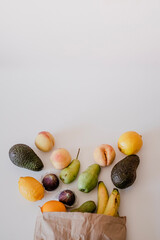 A variety of fruits in a crafted paper bag are lying on the table