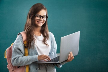 Portrait of smiling teen girl using a laptop computer, studying online