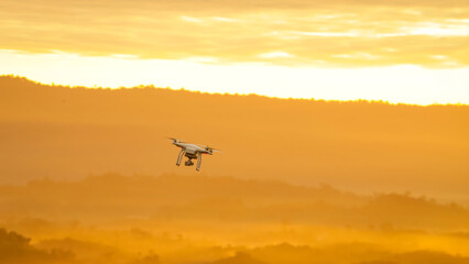 Fototapeta na wymiar flying drone on mountain at beautiful sunrise