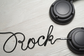 Headphones with Rock word shaped wire on the white wooden table.