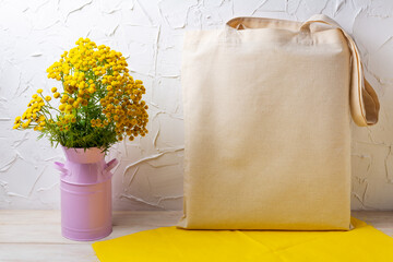 Rustic tote bag mockup with yellow flowers in the pink can