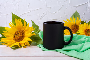 Black coffee mug mockup with green napkin and sunflowers
