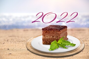 2022 Happy New Year concept with chocolate cake and on the beach