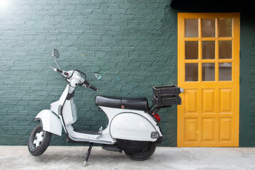 Fototapeta premium vintage style motorcycle park on the concrete floor in front of green brick wall and fresh yellow door beside