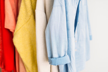 Collection of colorful clothes hanging on rack. Closeup
