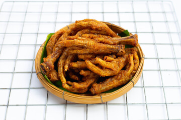 Fried chicken feet in bamboo basket on white background.