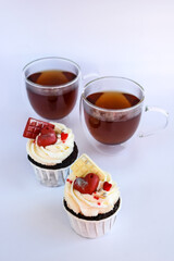 chocolate cupcakes with cream cheese icing and festive decor and tea in glass cups. Valentine's day or birthday dessert. A beautiful festive treat for a wedding or children's party.