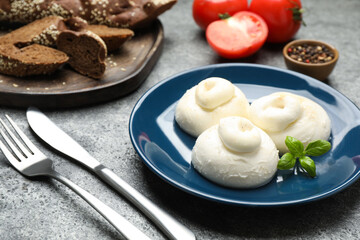 Delicious burrata cheese with basil on grey table